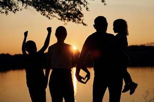 regardant le coucher du soleil. la famille de la mère, du père et des enfants est sur le camping photo