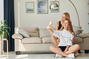 assis sur le sol. une adolescente avec sa mère est à la maison pendant la journée photo