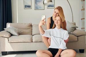 assis sur le sol. une adolescente avec sa mère est à la maison pendant la journée photo