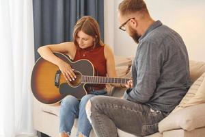 professeur de guitare montrant comment jouer de l'instrument à une jeune femme photo