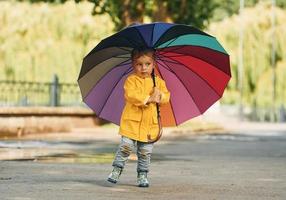 petit garçon en manteau jaune se promener à l'extérieur dans le parc après la pluie photo