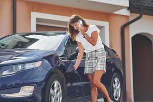 en attendant la charge de la voiture électrique. la femme est à l'extérieur avec son automobile moderne photo