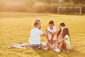 beau soleil. groupe d'enfants heureux est à l'extérieur sur le terrain de sport pendant la journée photo