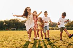 debout sur le terrain sportif. groupe d'enfants heureux est à l'extérieur pendant la journée photo