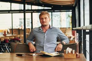 portrait d'un homme adulte assis à l'intérieur près de la table du café photo