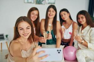 tenant des verres avec boisson. groupe de femmes heureuses qui est à un enterrement de vie de jeune fille photo