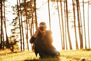 photographe professionnel avec appareil photo travaillant dans la forêt