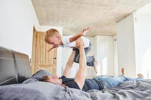 allongé sur le lit. père et fils sont à l'intérieur à la maison ensemble photo