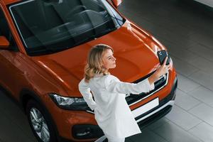 faire des selfies. femme en vêtements formels est à l'intérieur dans l'autosalon photo