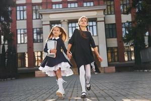 deux écolières courent dehors ensemble près du bâtiment de l'école photo