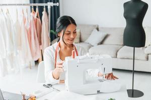 matériel professionnel. la couturière est dans son bureau avec des vêtements différents photo