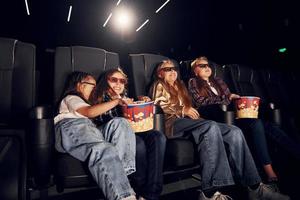 dans des vêtements décontractés. groupe d'enfants assis au cinéma et regardant un film ensemble photo