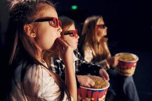 vue de côté. groupe d'enfants assis au cinéma et regardant un film ensemble photo