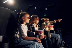 avec du pop-corn. groupe d'enfants assis au cinéma et regardant un film ensemble photo