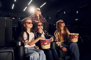 manger du pop-corn. groupe d'enfants assis au cinéma et regardant un film ensemble photo