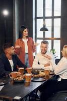 manger des aliments. groupe de jeunes amis assis ensemble au bar avec de la bière photo