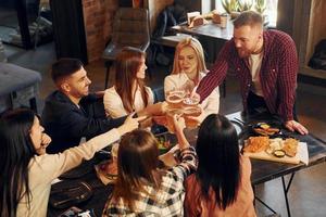 humeur agréable. groupe de jeunes amis assis ensemble au bar avec de la bière photo