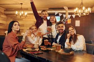 fans de football. groupe de jeunes amis assis ensemble au bar avec de la bière photo