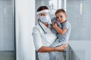 avec petit enfant dans les mains. médecin professionnel en blouse blanche est à la clinique photo