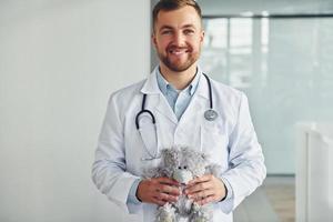 avec ours en peluche. médecin professionnel en blouse blanche est à la clinique photo