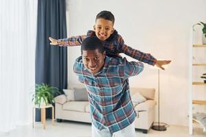 s'amuser. père afro-américain avec son jeune fils à la maison photo