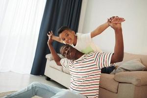 passer du temps actif le week-end. père afro-américain avec son jeune fils à la maison photo