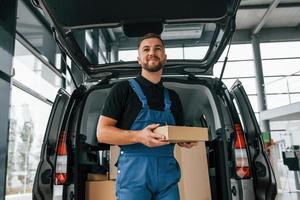 vue de face. livreur en uniforme est à l'intérieur avec voiture et avec commande photo