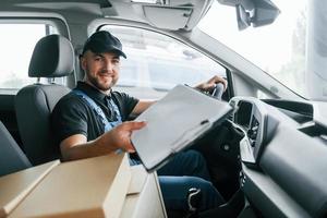 avec documents. livreur en uniforme est à l'intérieur avec voiture et avec commande photo