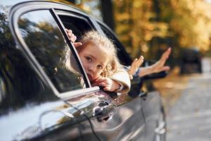 petite fille avec son frère assis dans la voiture et regardant par la fenêtre ouverte photo