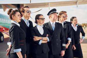 près de l'avion. équipage de travailleurs de l'aéroport en vêtements formels debout ensemble à l'extérieur photo