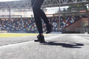 vue rapprochée des jambes du coureur en pantalon noir et chaussures qui est à l'extérieur sur la piste photo