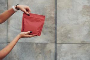 vue rapprochée des mains de la femme qui contient un paquet rouge de nouveau café photo