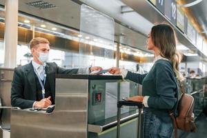 debout près de la table avec l'employé. jeune femme touriste est à l'aéroport pendant la journée photo