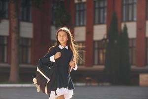 écolière marche à l'extérieur près du bâtiment de l'école photo