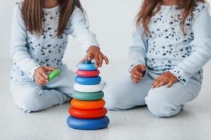 jouer avec un jouet. deux jolies petites filles à l'intérieur à la maison ensemble. les enfants s'amusent photo