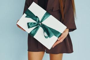 vue rapprochée d'une jeune femme qui se tient contre le mur avec une boîte-cadeau dans les mains photo