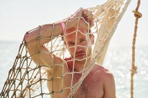 temps chaud. jeune homme européen passe des vacances et profite de temps libre sur la plage de la mer photo