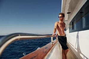 temps chaud. jeune touriste masculin est sur le yacht sur la mer. conception de vacances photo