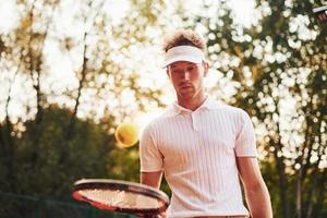 jeune joueur de tennis en vêtements sportifs est sur le terrain à l'extérieur photo
