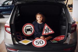 portrait d'une petite fille mignonne qui tient des panneaux routiers dans les mains dans un salon automobile photo