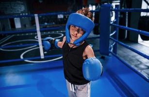 petit garçon en tenue de protection et avec formation de saignement de nez dans le ring de boxe photo