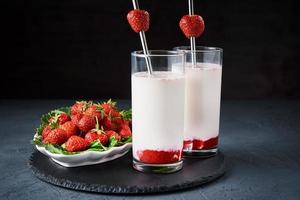 smoothie au lait de fraise en verre avec paille sur fond sombre photo