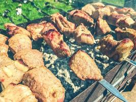 le kebab de viande sur des brochettes se trouve sur le gril. une croûte est cuite sur des morceaux de viande. grillades, barbecue dans la cour de la maison. préparer le dîner photo