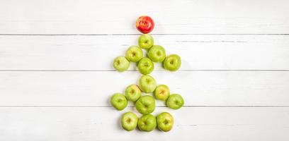 arbre de noël comestible de pommes vertes avec pomme rouge comme étoile sur une table en bois blanche. bannière. espace de copie. photo
