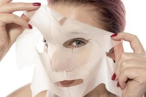 soins du visage et soins esthétiques. femme avec un masque hydratant en feuille sur son visage isolé sur fond blanc photo