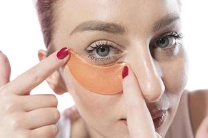 femme avec des patchs cosmétiques hydratants sur la peau sous les yeux. isolé sur fond blanc photo