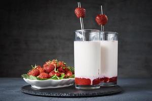 smoothie au lait de fraise en verre avec paille sur fond sombre photo