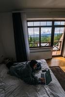 jeune femme travaillant sur un ordinateur portable en position couchée sur le lit photo