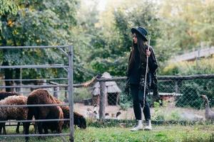 jeune femme près d'un enclos avec des moutons dans une ferme photo