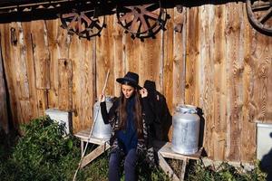 femme assise sur un banc avec des bidons de lait dans une ferme photo